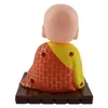 The back view of a solar-powered wackelfigur (nodding figure) of a Buddha, sitting on a brown base. Produktbild-Vorschau