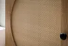 A close-up view of a wooden sideboard with a rattan woven panel and a black knob. Produktbild-Vorschau