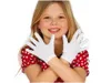A young girl wearing white gloves and a red polka dot dress, posing with her hands in front of her. Anteprima dell’immagine prodotto