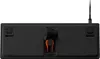 The underside of a black keyboard with an orange cable management clip. Náhľad obrázku produktu