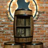A wooden barrel-shaped bar cabinet with shelves, set against a brick wall with a decorative guitar silhouette and lighting. Náhled obrázku produktu