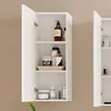 A white bathroom cabinet with its door open, displaying various toiletries on its shelves. Voir les images du produit
