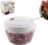 A manual food chopper filled with chopped red onions, with a hand pulling the cord to operate it. A box for the product is visible in the upper left corner. Náhled obrázku produktu