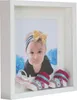 A framed baby photo with baby socks and a pacifier. Produktbild-Vorschau