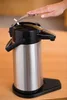 A hand pressing down on the lid of a silver and black airpot. Produktbild-Vorschau