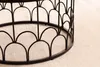 Close-up of the base of a black metal table with a decorative scalloped design, resting on a light beige carpet. Produktbild-Vorschau