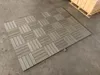 Decking tiles laid out on a concrete floor with a pallet of boxes in the background. Náhled obrázku produktu
