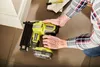 A person is using a Ryobi nail gun to attach trim to a wall. Anteprima dell’immagine prodotto