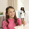 A young girl is holding a Barbie doll in a glittery cowgirl outfit. Produktbild-Vorschau