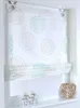 A white Roman blind with a circular pattern in turquoise and beige, hanging in a window frame. Produktbild-Vorschau