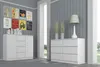 A white dresser with drawers is shown in a room with grey walls and framed pictures on the wall. Voir les images du produit