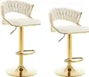 Two cream-colored bar stools with gold metal frames and bases are shown against a white background.
