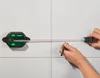 A person is using a PARKSIDE laser level and tape measure to mark a line on a tiled wall. Produktbild-Vorschau