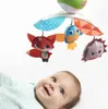A baby looking up at a mobile with stuffed animal toys. Voir les images du produit