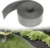 A roll of grey plastic garden edging is shown in the upper part of the image, with a garden scene in the lower part, featuring a wheelbarrow with soil and a shovel, and a flower bed with green plants bordered by the edging. Voir les images du produit
