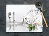 A diamond, cutlery, garlic, and herbs are arranged on a white surface, with a wooden spoon in the background. Produktbild-Vorschau