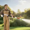 A man is using a telescopic spray lance to water a lawn in a garden. Produktbild-Vorschau