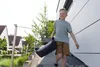 A young boy is walking up stairs carrying a car seat booster. Produktbild-Vorschau