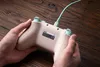 Hands holding a game controller on a wooden surface. Produktbild-Vorschau