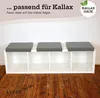 A white Kallax shelf unit with three gray seat cushions on top, set against a white wall and wooden floor. Produktbild-Vorschau