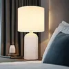 A bedside table with a lamp and a small vase. Anteprima dell’immagine prodotto