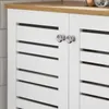 A close-up view of a white cabinet with louvered doors and natural wood top, featuring two round chrome knobs. Náhled obrázku produktu