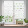 A close-up view of two white roller blinds with a wave pattern, covering a window with a view of greenery outside. A vintage radio and a decorative sheep are on the windowsill. Produktbild-Vorschau