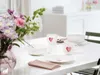 A table setting with floral arrangements and heart-themed tableware. Produktbild-Vorschau