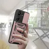 A hand holding a rose gold phone case with a ring holder, with a blurred interior background. Produktbild-Vorschau