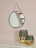 A round mirror hangs on a pink wall above two decorative vases on a white shelf. Produktbild-Vorschau