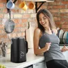 A woman dancing in a kitchen next to a black electric kettle. Náhľad obrázku produktu