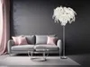 A modern living room with a gray sofa, pink pillows, a glass coffee table, and a floor lamp. Produktbild-Vorschau