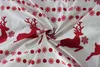 A close-up of white fabric with a red pattern of reindeer and snowflakes. Podgląd zdjęcia produktu