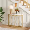 A console table with a marble top and gold metal frame is placed in a hallway next to a staircase. A lamp, a vase of flowers, and a framed picture are on the table. A potted plant is to the left of the table. Podgląd zdjęcia produktu