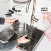 A person is filling a pot with water from a faucet in a kitchen sink, with fondue forks and a fondue pot accessory nearby. Produktbild-Vorschau