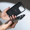 A person's hands are holding a phone case and a phone, demonstrating how they fit together. Produktbild-Vorschau