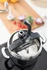 A close-up shot of a pressure cooker on a stovetop, with ingredients like garlic, tomatoes, and onions on a wooden cutting board in the background. Anteprima dell’immagine prodotto