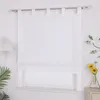 A white Roman blind is installed on a window, with a lamp on the left and a vase with flowers on the right. Produktbild-Vorschau