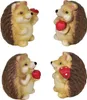 Four ceramic hedgehog figurines, each holding a red object that appears to be an apple or mushroom. Náhľad obrázku produktu