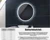 A round LED mirror is mounted on a dark tiled wall above a sink. Produktbild-Vorschau