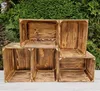 Several wooden crates are stacked in front of a green hedge. Produktbild-Vorschau