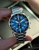 A close-up shot of a Citizen Eco-Drive Chronograph watch held by a person's fingers. Produktbild-Vorschau