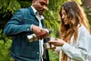 A man and a woman are outdoors, with trees in the background. The man is pouring a drink from a thermos into a cup held by the woman. Voir les images du produit