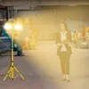 A woman in business attire walks through a warehouse, holding a tablet, while a bright work light illuminates the scene. Náhľad obrázku produktu