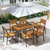 An outdoor dining set with a table, chairs, and umbrella, set in a garden with plants. Produktbild-Vorschau