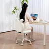 A woman is sitting at a desk and using a laptop, with a white bunny-eared chair in the foreground. Podgląd zdjęcia produktu