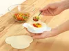 Hands filling a small tortilla with chopped bell peppers using a spoon and a tortilla press. Produktbild-Vorschau