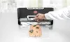 A hand is shown using a vacuum sealer to seal a piece of salmon in a plastic bag. Podgląd zdjęcia produktu