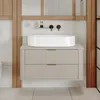 A modern bathroom vanity with a white vessel sink and matte beige drawers, framed by wooden elements. Anteprima dell’immagine prodotto