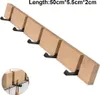 A wooden wall-mounted coat rack with five black hooks, presented against a white background. A small inset image shows a close-up of the rack and hooks, with items hanging from them. Produktbild-Vorschau